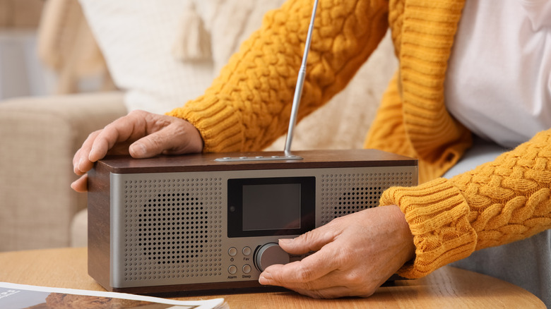A hand turning the volume dial of a radio
