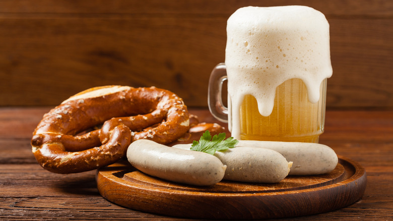 Bratwurst sausages and a pretzel served with beer on a wooden platter