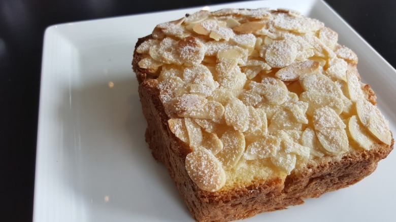A slice of bostock, covered with sliced almonds.