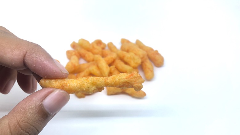 Fingers holding a Cheeto