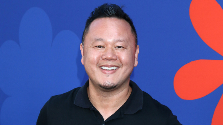 Jet Tila smiles against a blue and red backdrop