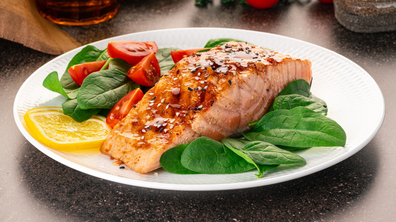 Baked for fried salmon served on top of a plate of vegetable salad.