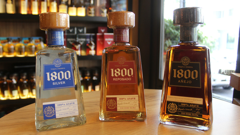 Three bottles of 1800 tequila in silver, reposado, and añejo