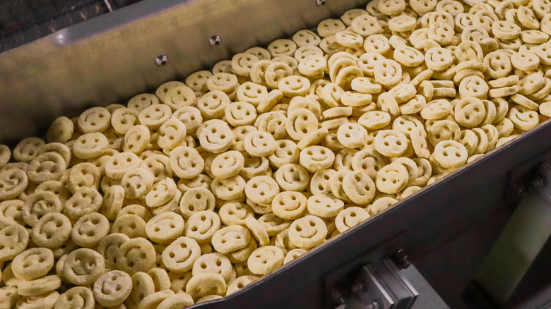 Smiley fries piled up on a conveyor belt