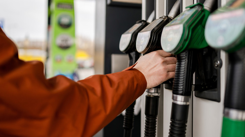 A man grabs a fuel pump at a gas station.