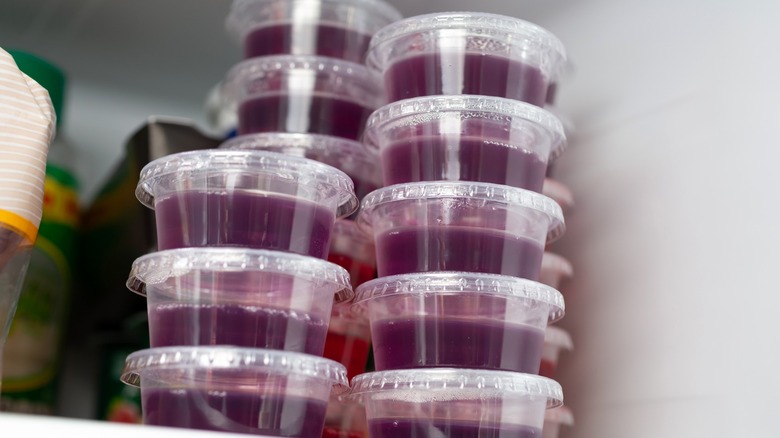 Jell-O shots with lids stacked and stored in a fridge