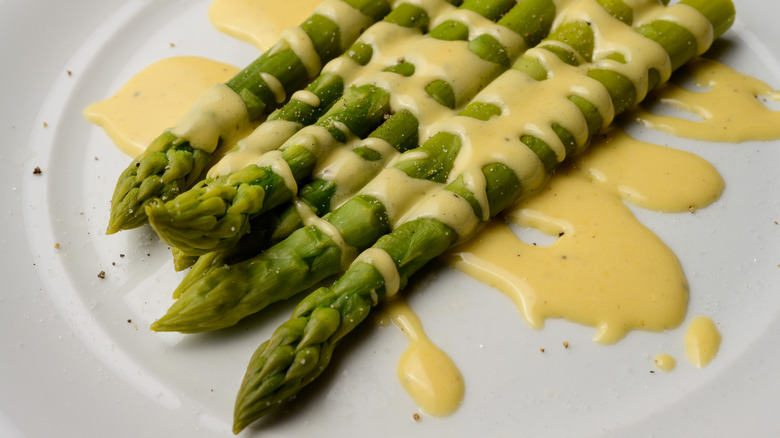 asparagus with hollandaise sauce on a white plate