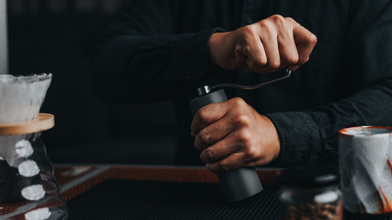 A barista grinds coffee by hand