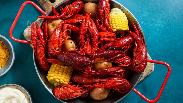 A top-down view of a stock pot full of crawfish, potatoes, and corn.