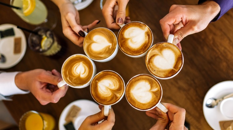 Overhead view of hands clinking coffee cups together