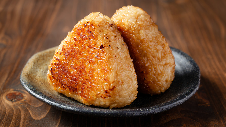 Yaki or grilled onigiri without nori on a black speckled plate.
