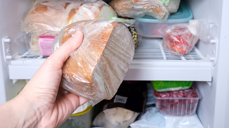 Hand pulling partially loaf of bread from freezer