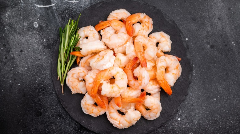 Cooked shrimp on black plate with rosemary sprig on top