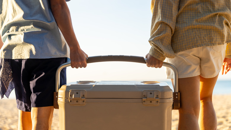 Couple carries a cooler on the beach