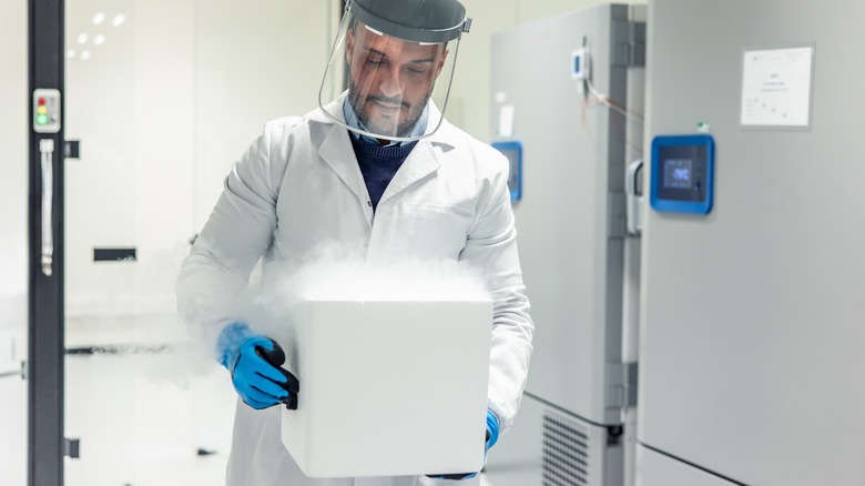 A man in a lab coat carries a box of dry ice