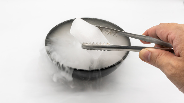 Tongs lifting a cube of dry ice