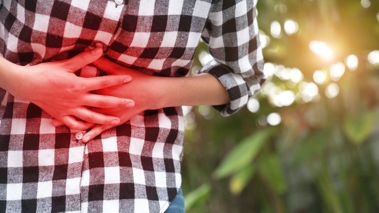 A person with a stomach ache clutching their midsection with a red glow
