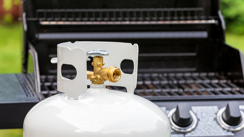 An open propane grill with a gas tank