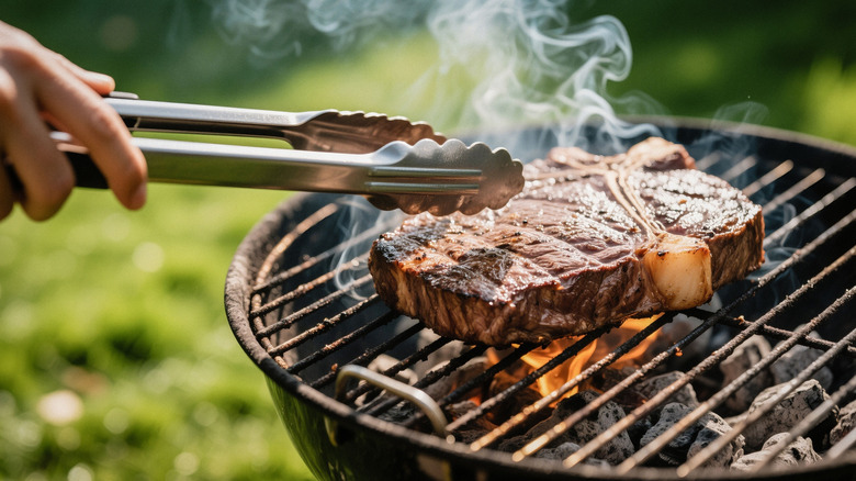 A t-bone steak being cooked on a charcoal grill