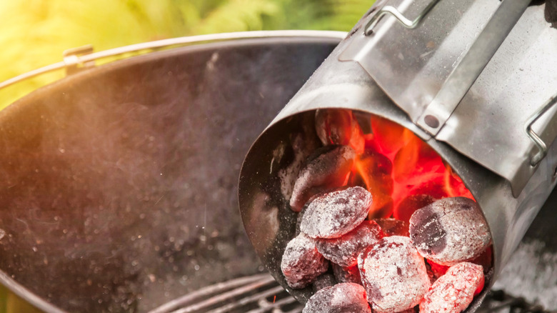 Glowing red charcoal is being poured from a chimney starter
