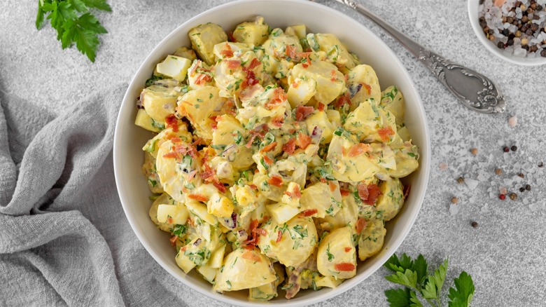 Potato salad with veggies and eggs in white bowl