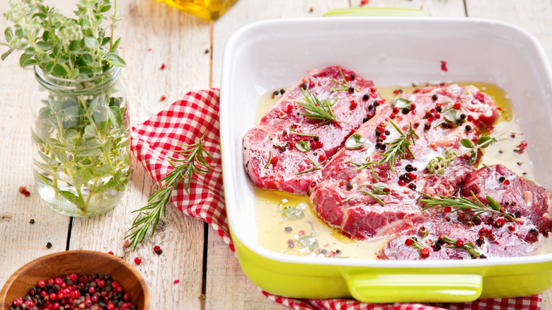 Three slaps of steak marinating in a large dish.