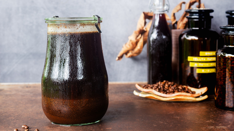 A jar of cold brew coffee on a counter near bottled ingredients