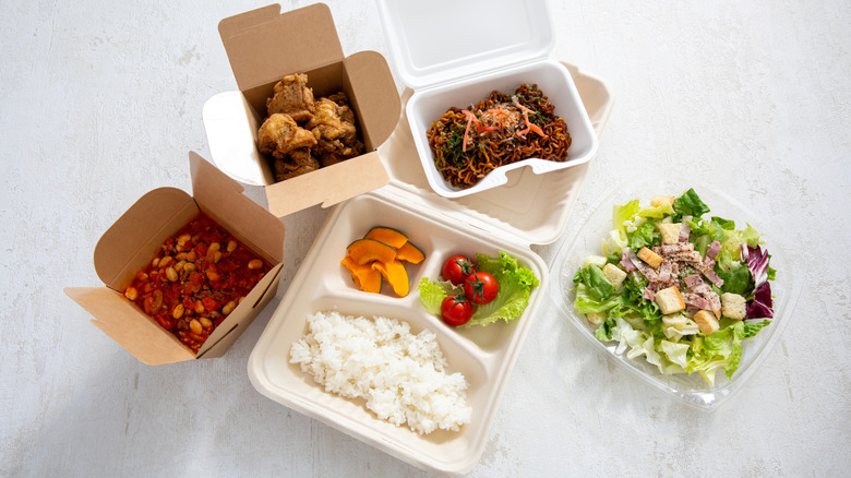 Restaurant leftovers in paper containers on white surface
