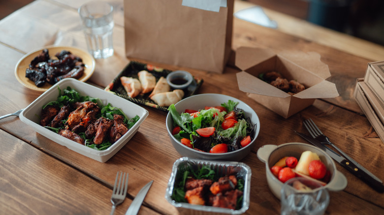 Various food items sitting on a table in takeout boxes