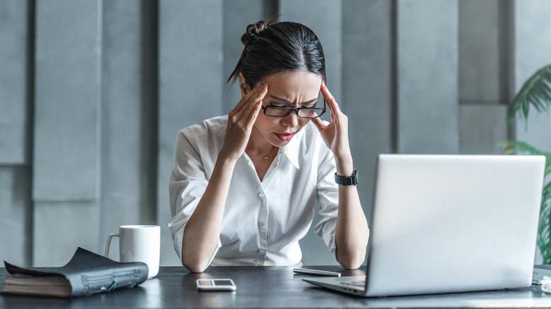 Young woman in the office with a headache