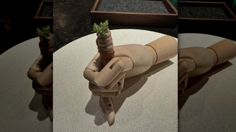 An appetizer of foie gras mousse in a chicken-skin cone held by a wooden hand at Konro in West Palm Beach.