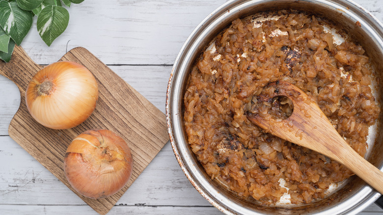 Whole raw onions next to large pan of caramelized onions