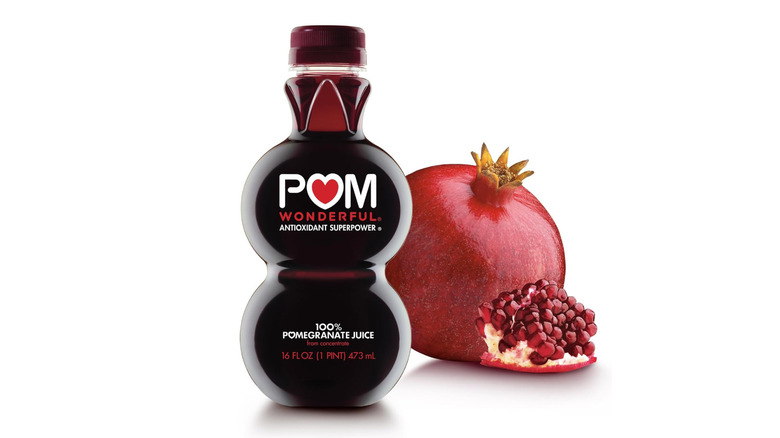 A bottle of POM Wonderful juice with a whole pomegranate on a white background.