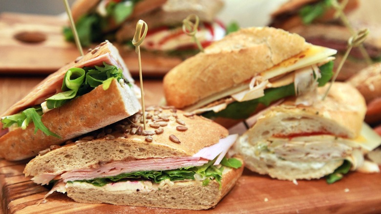 A platter of deli sandwiches stacked on top of each other.