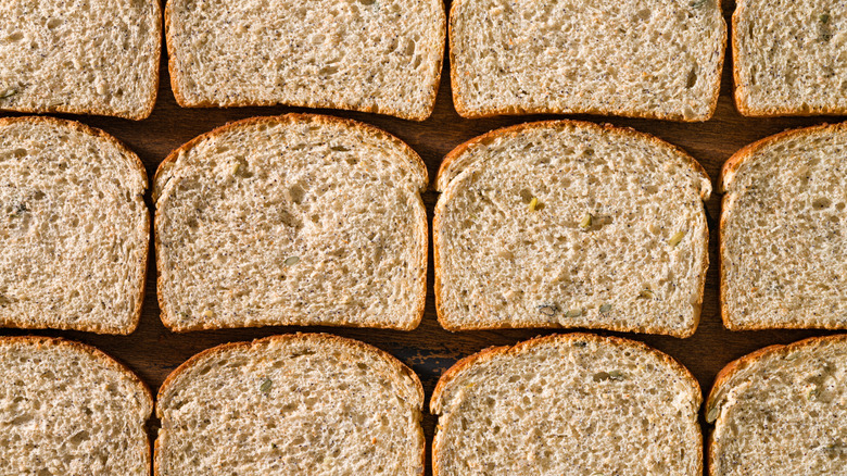 Slice of wheat bread laying flat on a wooden board