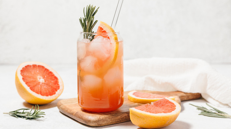Orange cocktail in clear glass with rosemary and fresh grapefruit