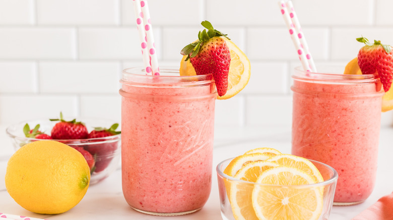 Strawberry lemon smoothies with straws in mason jars, pictured with fruit