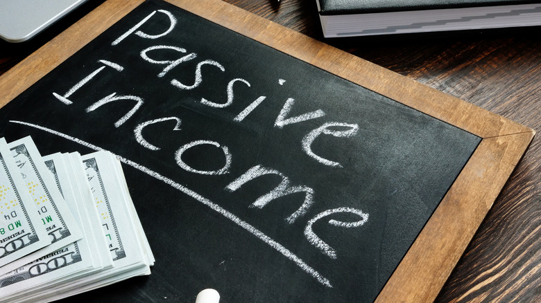 Chalkboard with passive income written on it and one hundred dollar bills in the corner