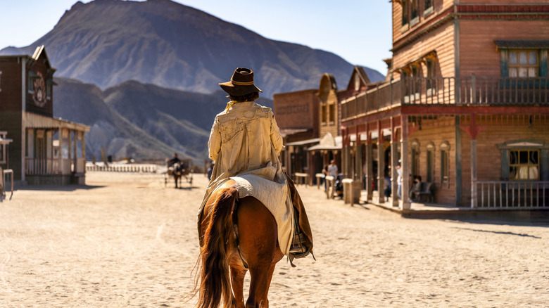 A cowboy on horseback riding into town