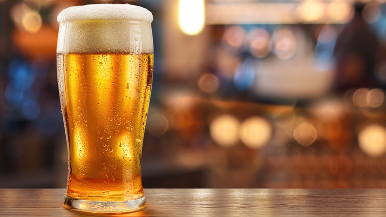 Beer on a wooden bar with a full, frothy head