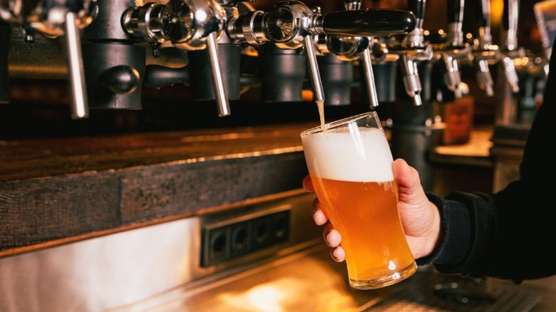 A bartender pouring beer from a tap.