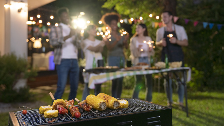 A group of friends enjoying food at a backyard cookout.