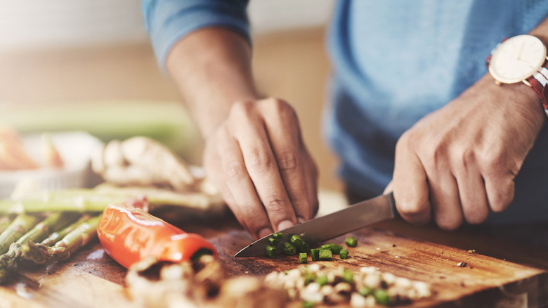 Hands chopping vegetables on a cutting board