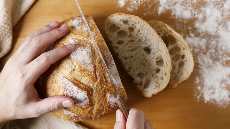 Person slicing loaf of sourdough