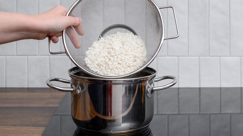 Person putting rice into stock pot