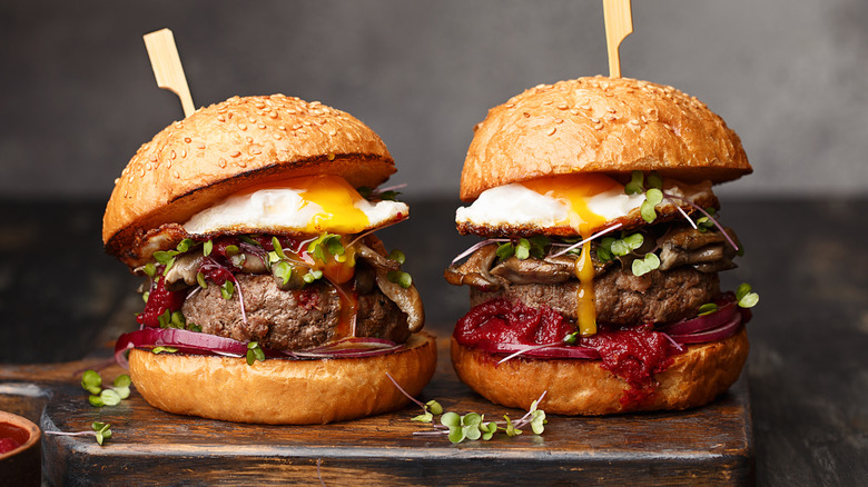 Two homemade beef burgers with egg and red onion