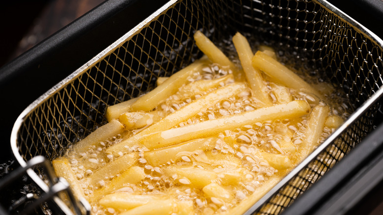 French fries in a basket frying in hot oil in the fryer