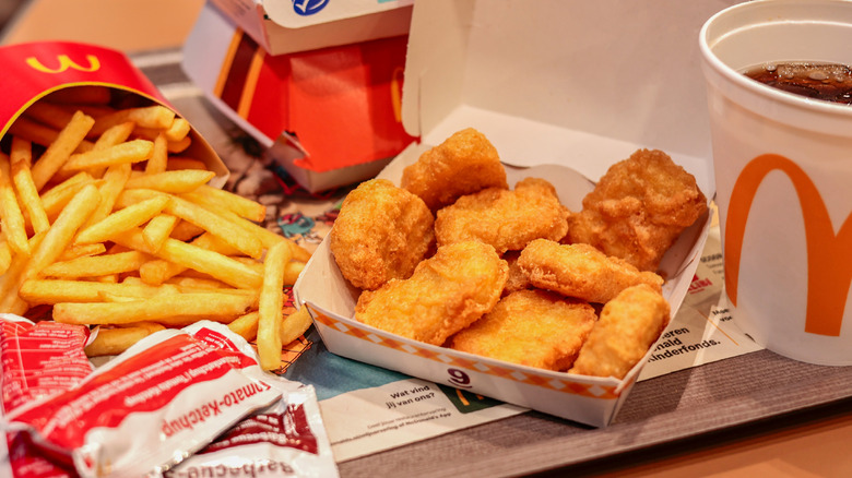 A meal from McDonald's with fries, chicken nuggets, and a soda.