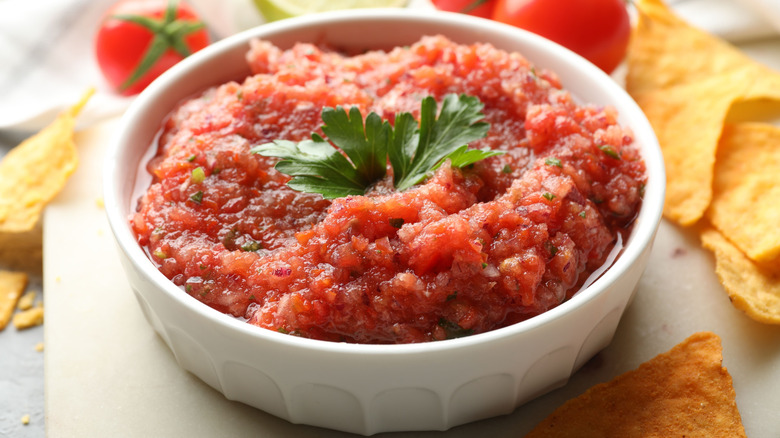 Salsa with a cilantro leaf garnish in a white bowl.