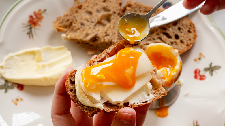 A person spooning egg yolk over bread and cheese
